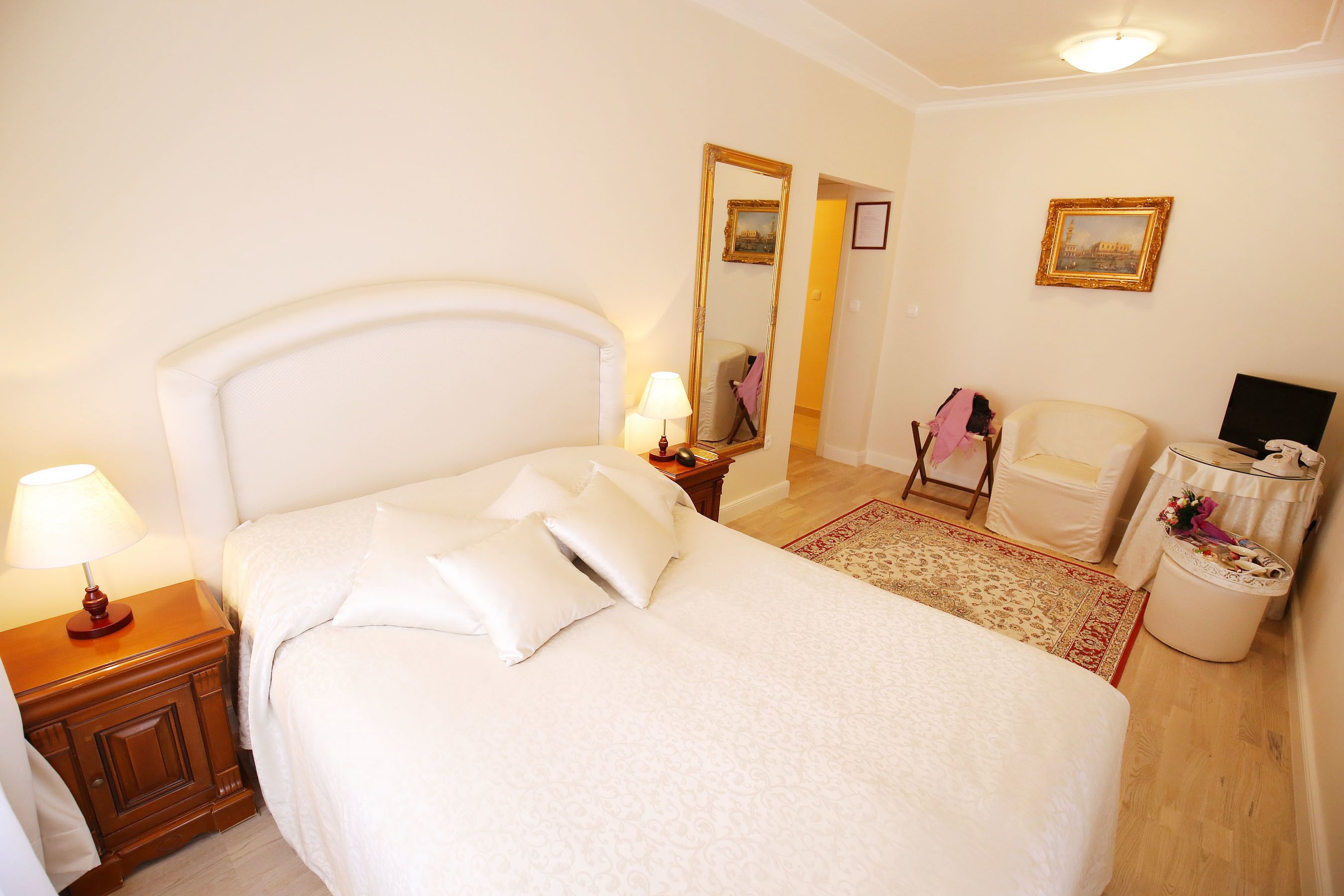 Une chambre à coucher bien rangée, avec un grand lit, des tables de chevet, une chaise et une petite table avec une lampe.