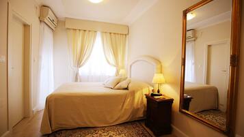 A hotel room with a bed, a nightstand, a mirror, and a window with curtains.
