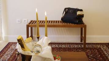 A table with a champagne bucket, two lit candles, and a dessert tray.