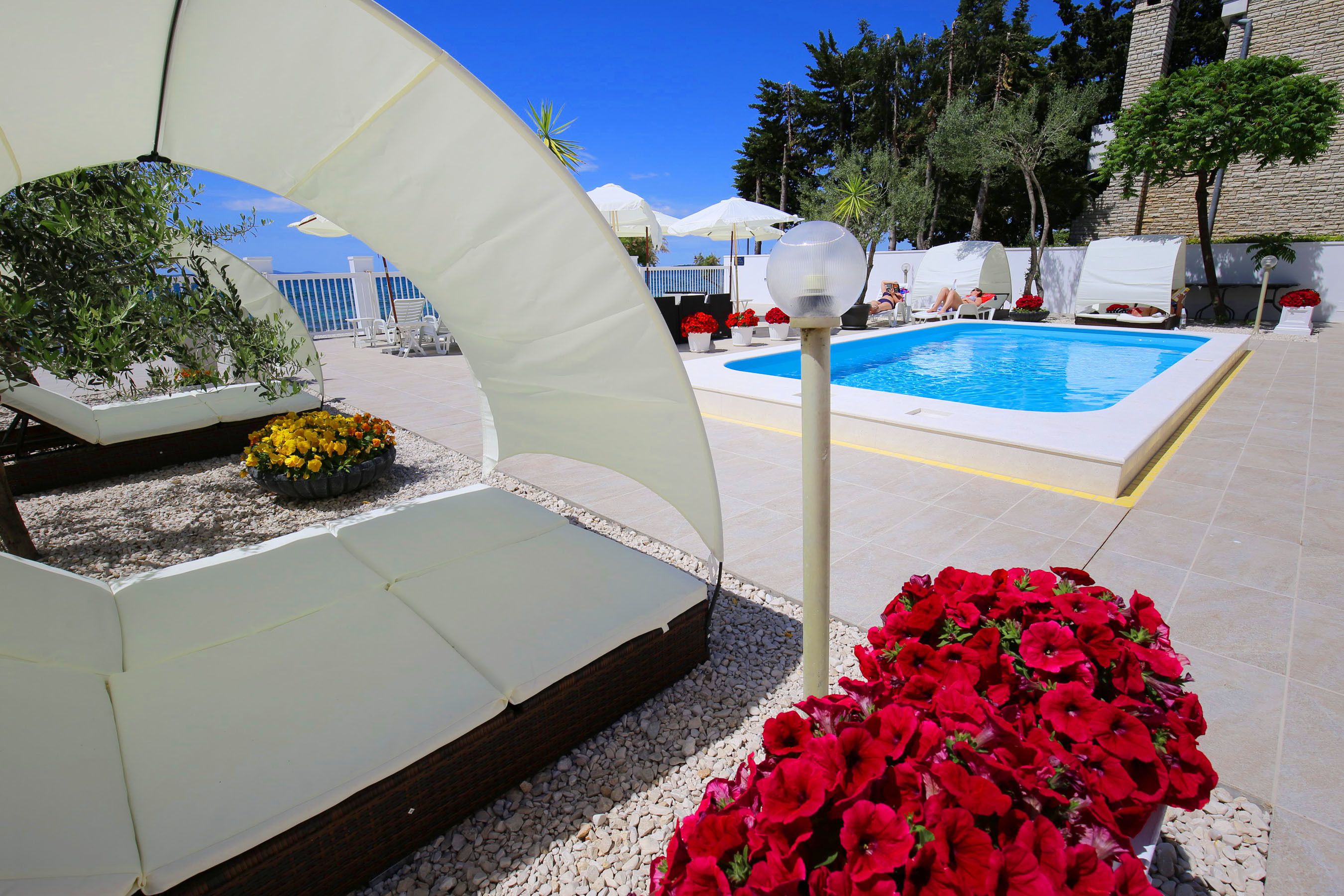 A pool area with lounge chairs, umbrellas, and potted plants.