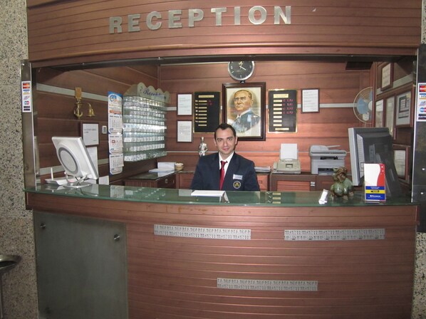 Welcome to our reception area, where friendly staff are available to assist with your stay. The area features a comfortable seating space with a bulletin board and a fan.