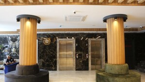 A lobby with two large columns, a reception desk, and two elevators. - Alican Hotel (Izmir)