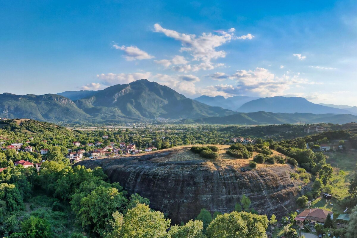 A mountainous landscape with a village and a prominent rock formation.