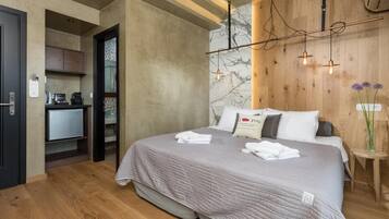 A modern hotel room with a bed, bedside table, and a small kitchenette.