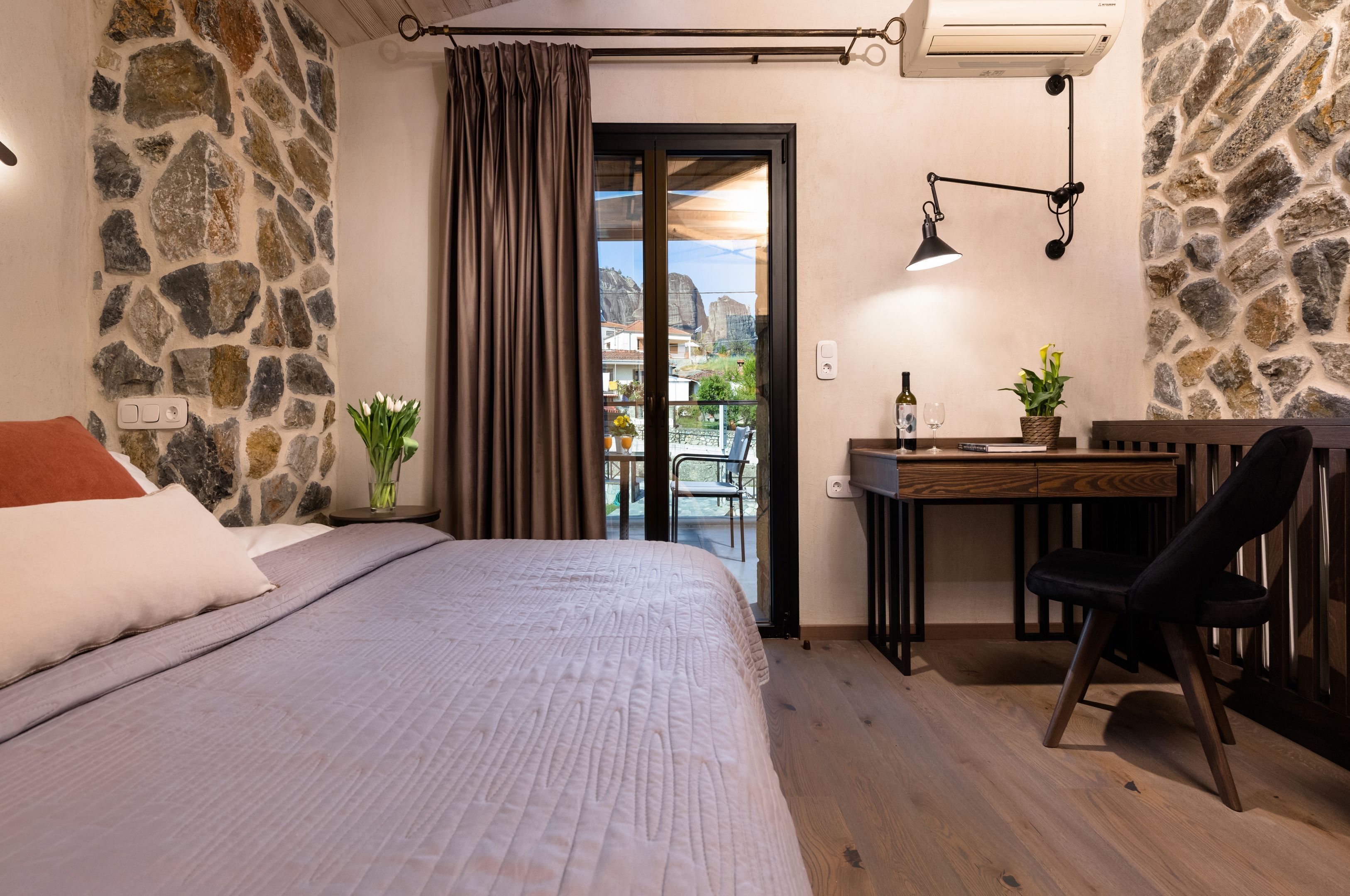 Een slaapkamer met een bed, een bureau, een stoel, een kamerplant en uitzicht op buiten.