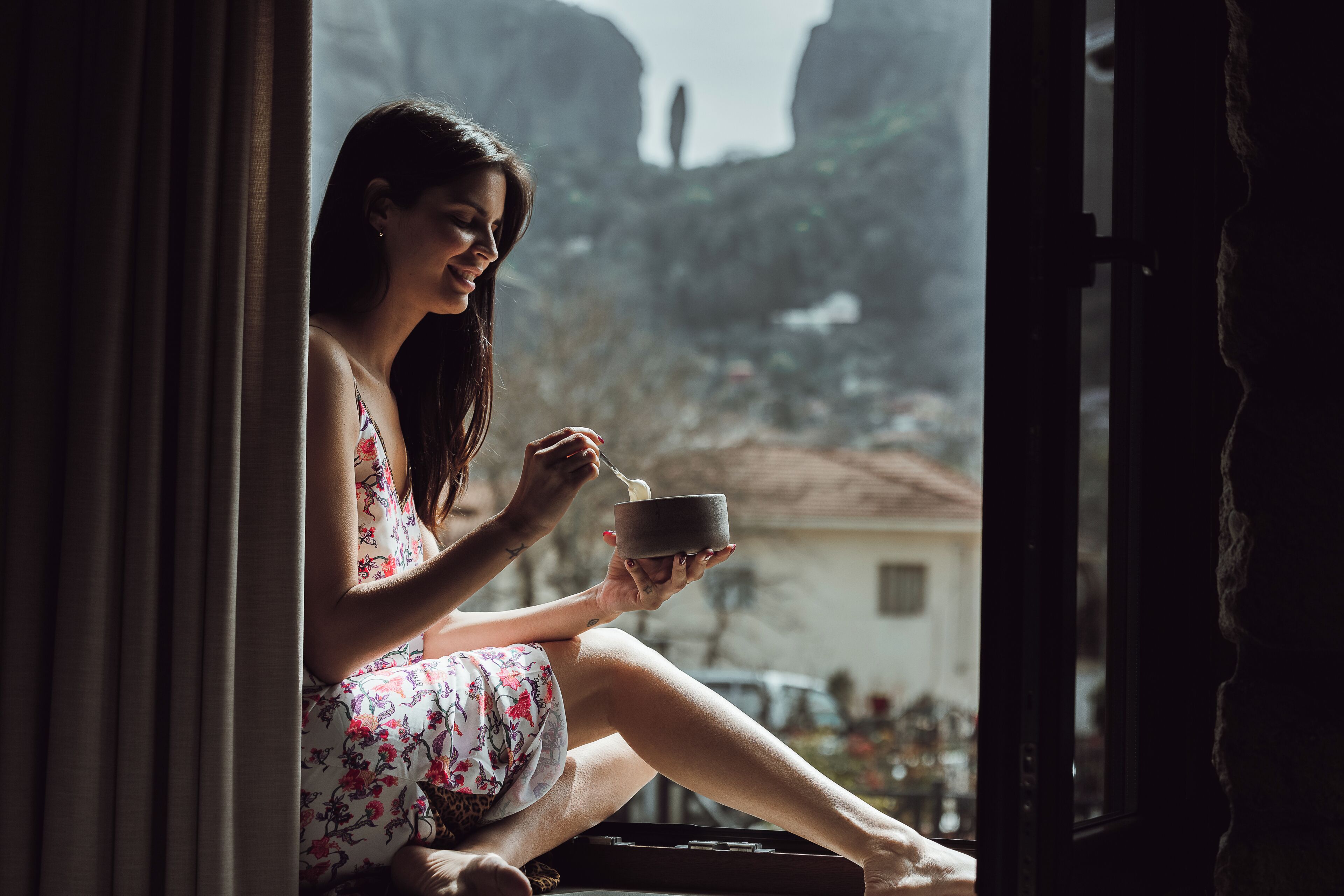 Una persona sentada junto a una ventana con vista a un paisaje montañoso.