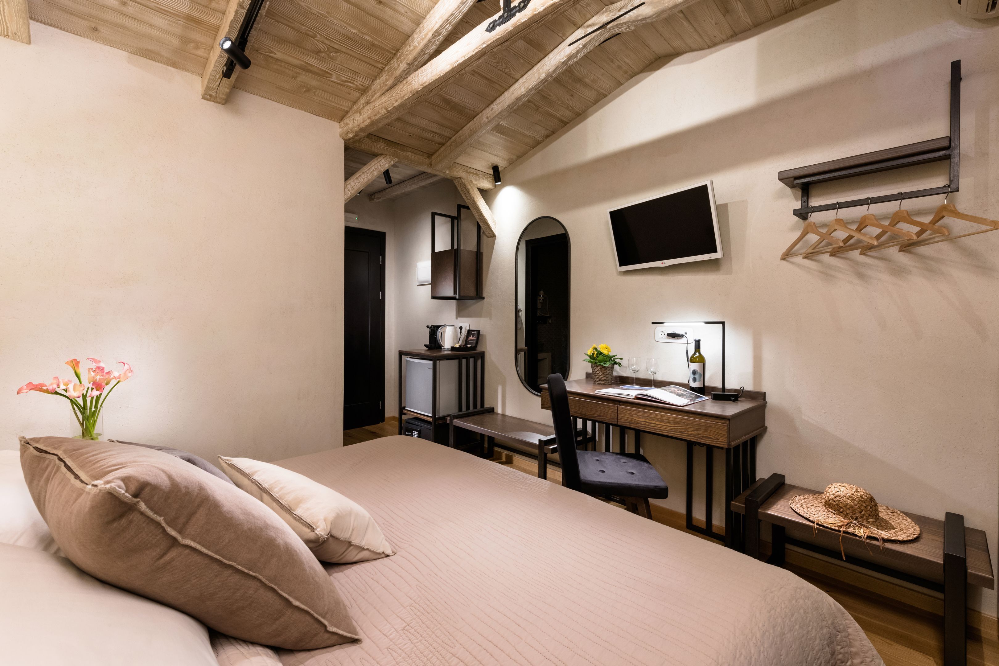 Une chambre à coucher comprenant un lit, un bureau, une chaise, un téléviseur et une étagère avec des cintres.