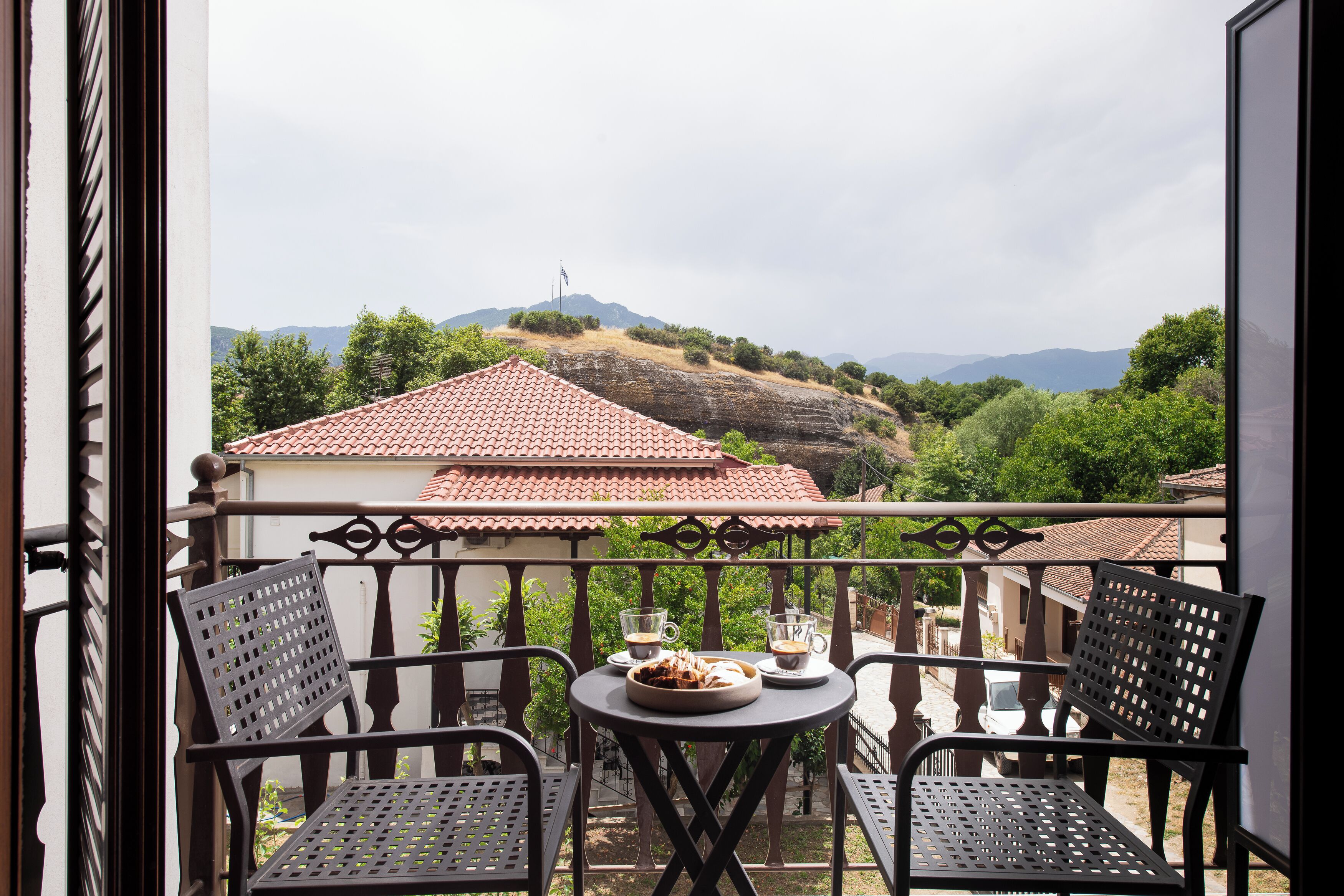 A balcony with two chairs, a table, and a plate of food.