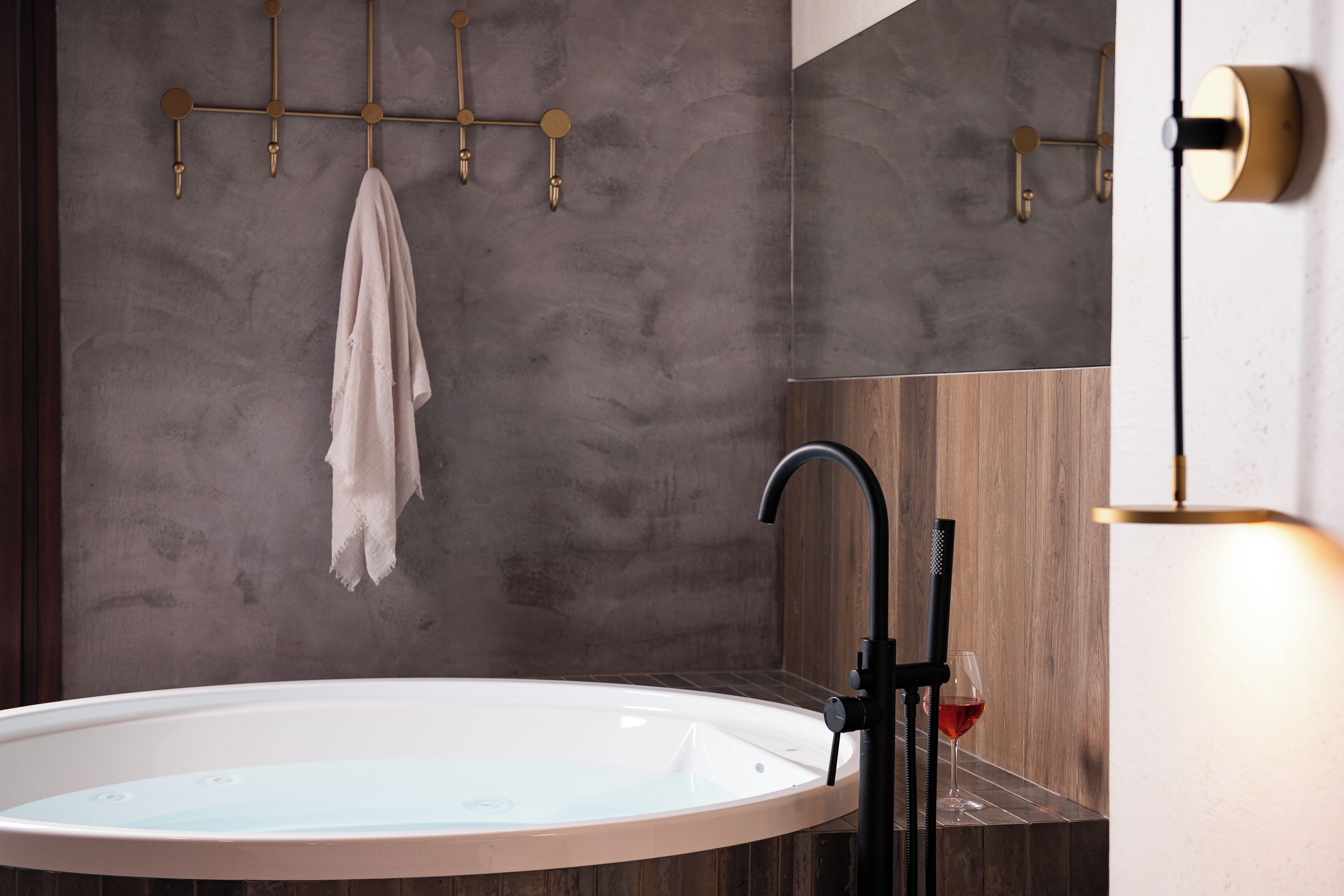 Ein modernes Badezimmer mit einer freistehenden Badewanne, einem Handtuchhalter und einem Weinglas auf der Ablagefläche.