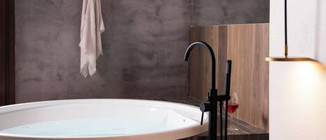 Ein modernes Badezimmer mit einer freistehenden Badewanne, einem Handtuchhalter und einem Weinglas auf der Ablagefläche.