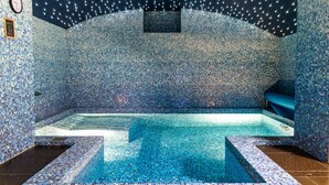 A mosaic-tiled room with a central pool, a clock on the wall, and a small window. - Gallery Park Hotel & SPA, a Châteaux & Hôtels Collection (Riga)