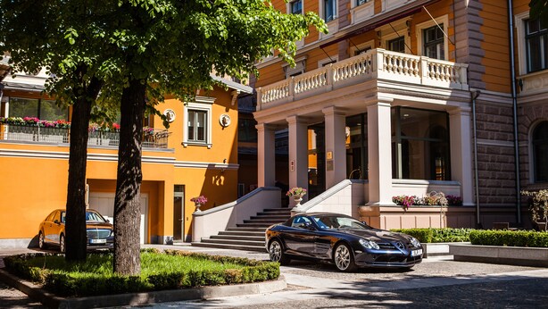 A hotel with a classic architectural style, featuring a grand entrance with steps leading to a covered area, and a car parked in front. - Gallery Park Hotel & SPA, a Châteaux & Hôtels Collection (Riga)
