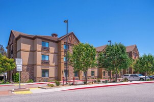 A multi-story hotel with a stone facade, balconies, and a clear blue sky.