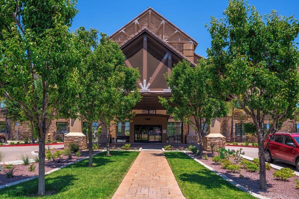 A building with a stone facade, a central entrance, and a paved walkway leading to it.