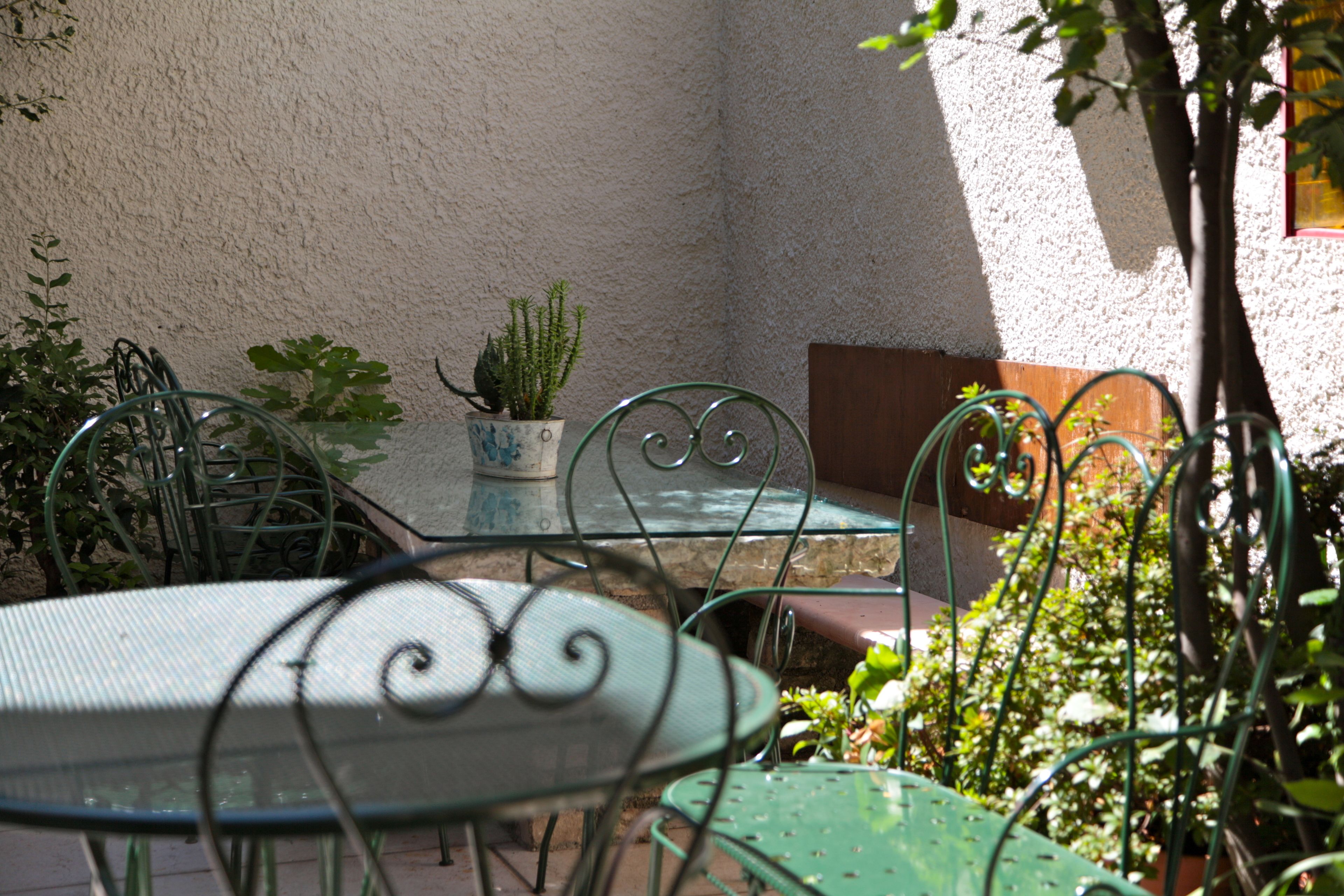 Ein Patio mit Metalltischen und -stühlen, Kübelpflanzen und einem Tisch mit einer Dekoration.