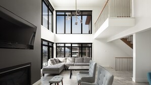 A modern living room with a sectional sofa, a flat-screen TV, and a staircase leading to an upper level.