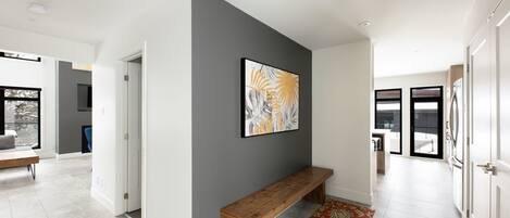 A modern hallway with a bench, a grey accent wall, and a large abstract painting.