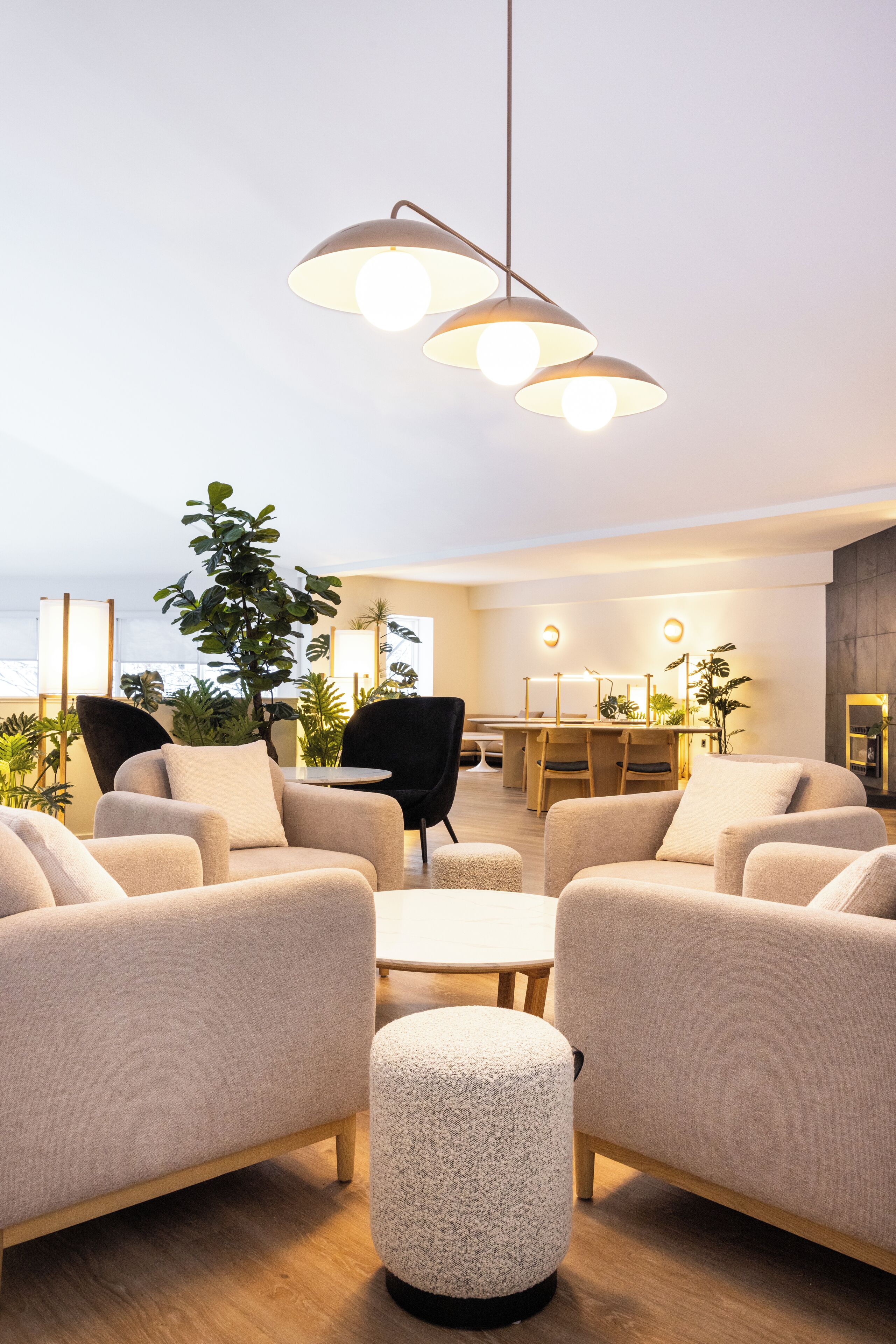 A modern living room with beige sofas, a round coffee table, and a hanging light fixture.