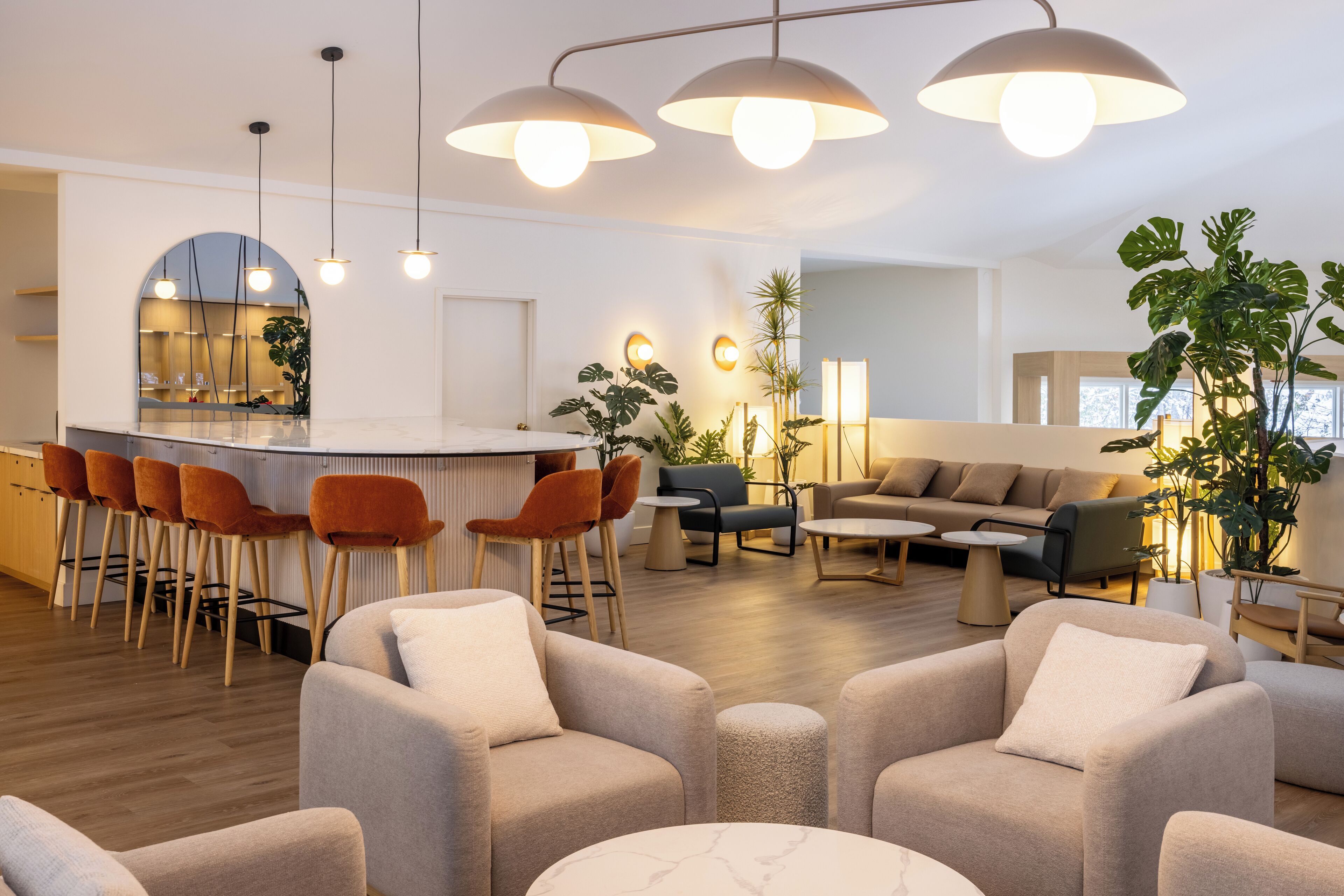 A modern living room with a bar area, comfortable seating, and a large plant.
