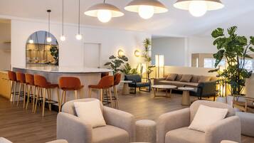 A modern living room with a bar area, comfortable seating, and a large plant.