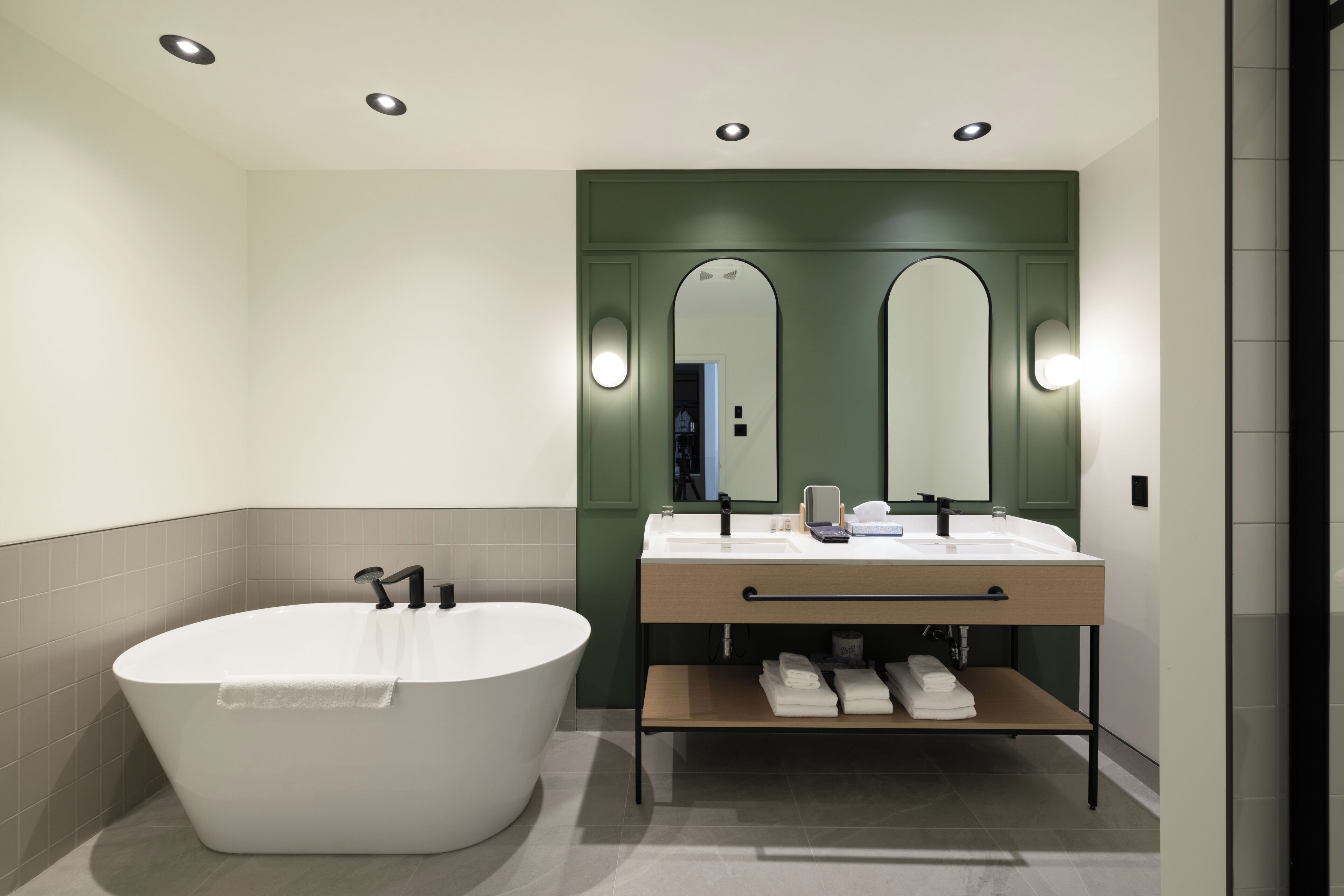 Une salle de bain moderne avec une baignoire sur pieds, deux vasques et un meuble-lavabo avec un miroir.