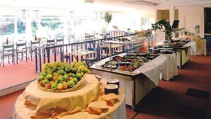 Montaje de buffet con diferentes opciones de comida y una exhibición de frutas.