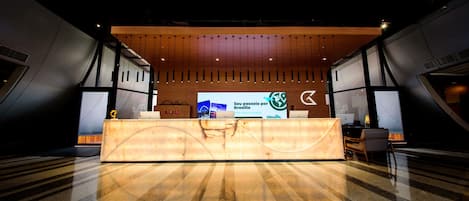 A reception desk with a wooden panel design, a large digital display, and a check-in counter.