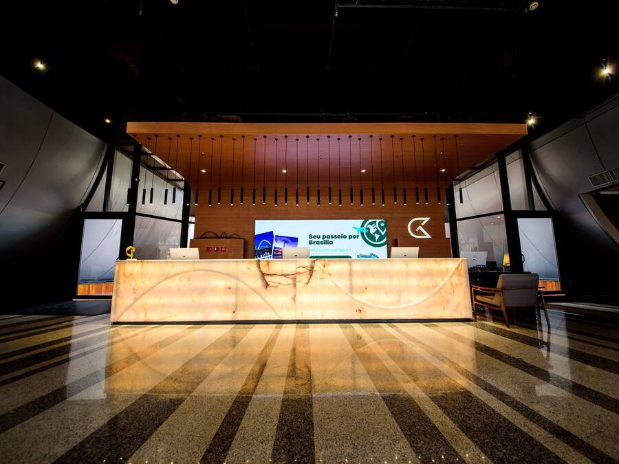 A reception desk with a wooden panel design, a large digital display, and a check-in counter.