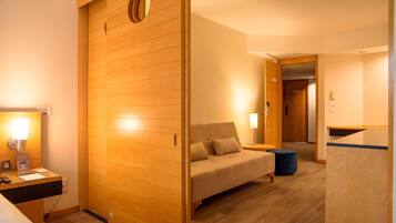 A hotel room with a wooden partition, a bed, a desk with a lamp, and a small round table.