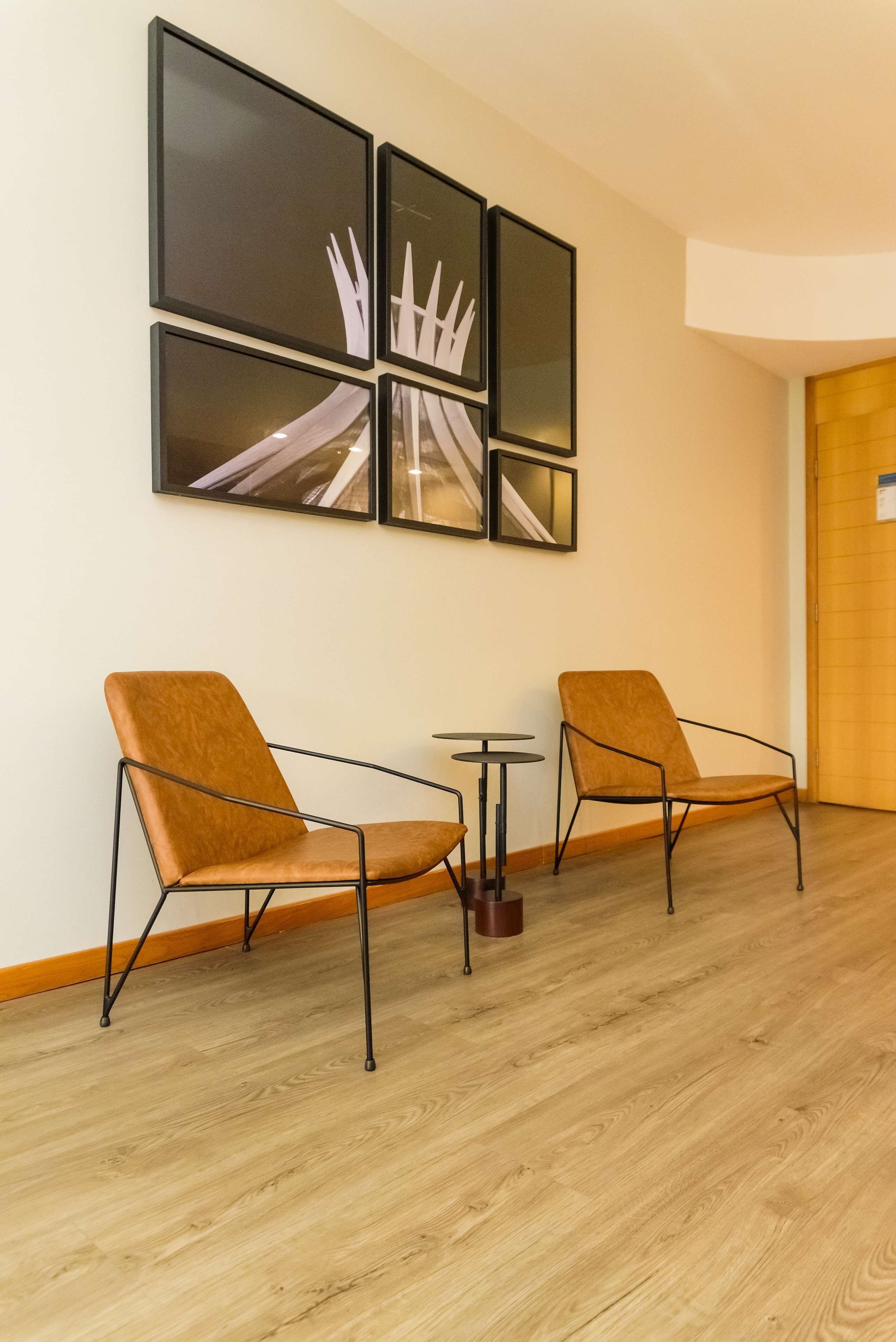 Une pièce comprenant deux fauteuils en cuir marron, une petite table ronde et une œuvre d’art accrochée au mur.