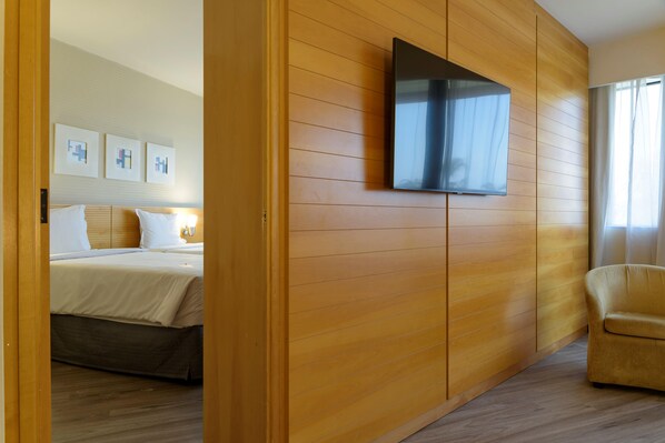 Una habitación de hotel con una cama, un televisor montado en una pared de madera y una silla.