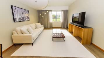 Uma sala de estar moderna com um sofá, uma mesa de centro e uma TV sobre um suporte de madeira.