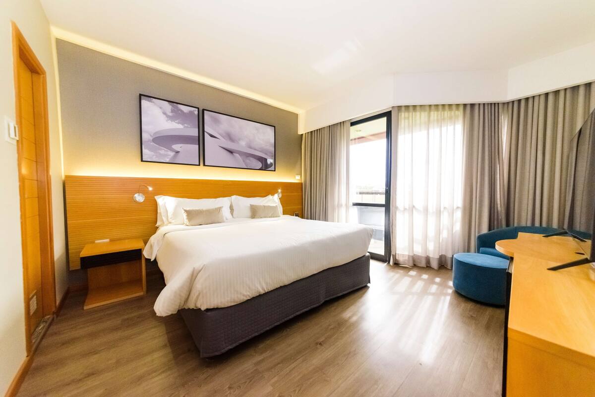 Habitación de hotel con una cama grande, un escritorio y una silla. Dos obras de arte decoran la pared sobre la cama.