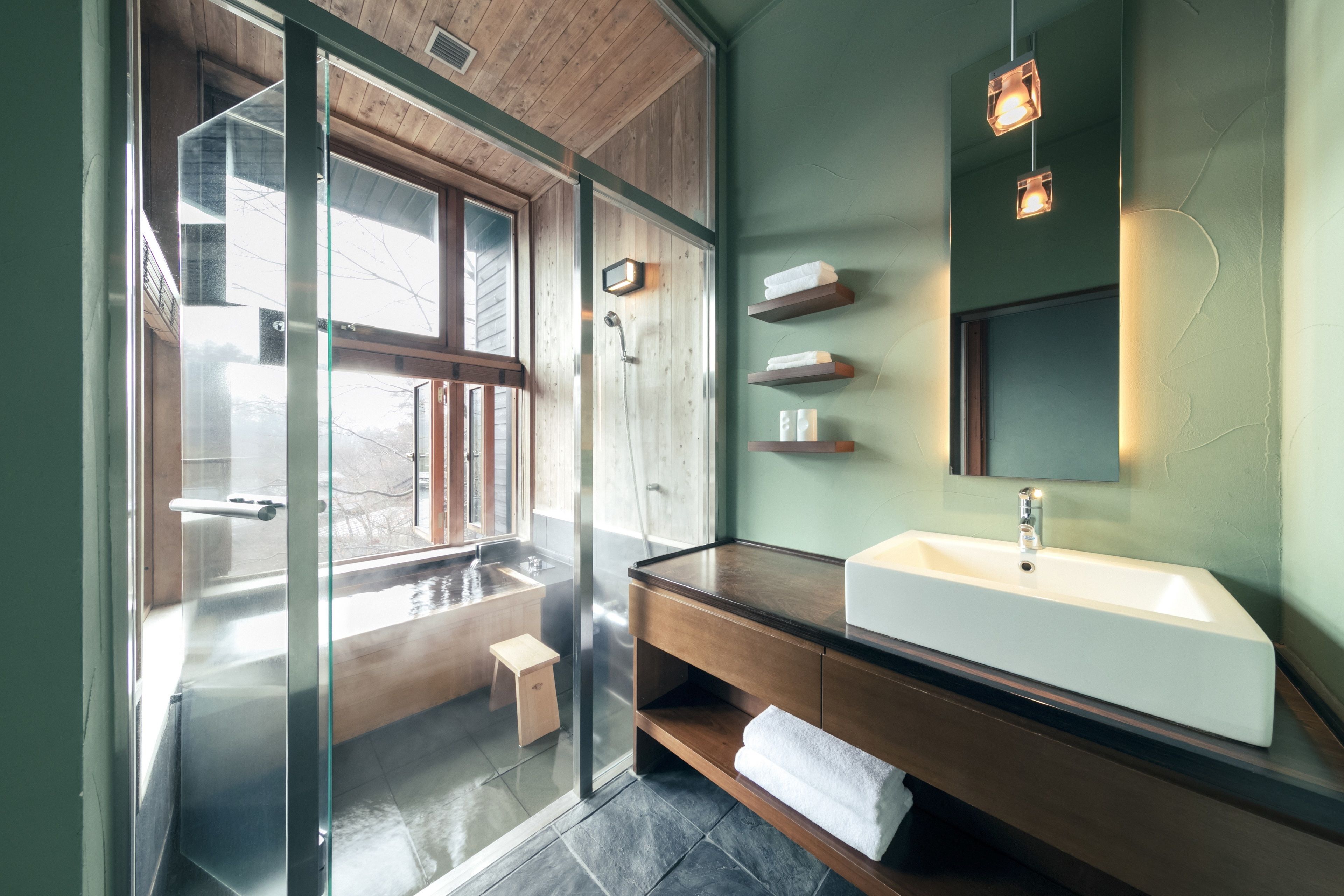 A modern bathroom with a glass-enclosed shower, a wooden vanity, and a large mirror.