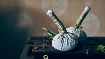 Two white massage balls tied with rope on a wooden surface with a rustic background.
