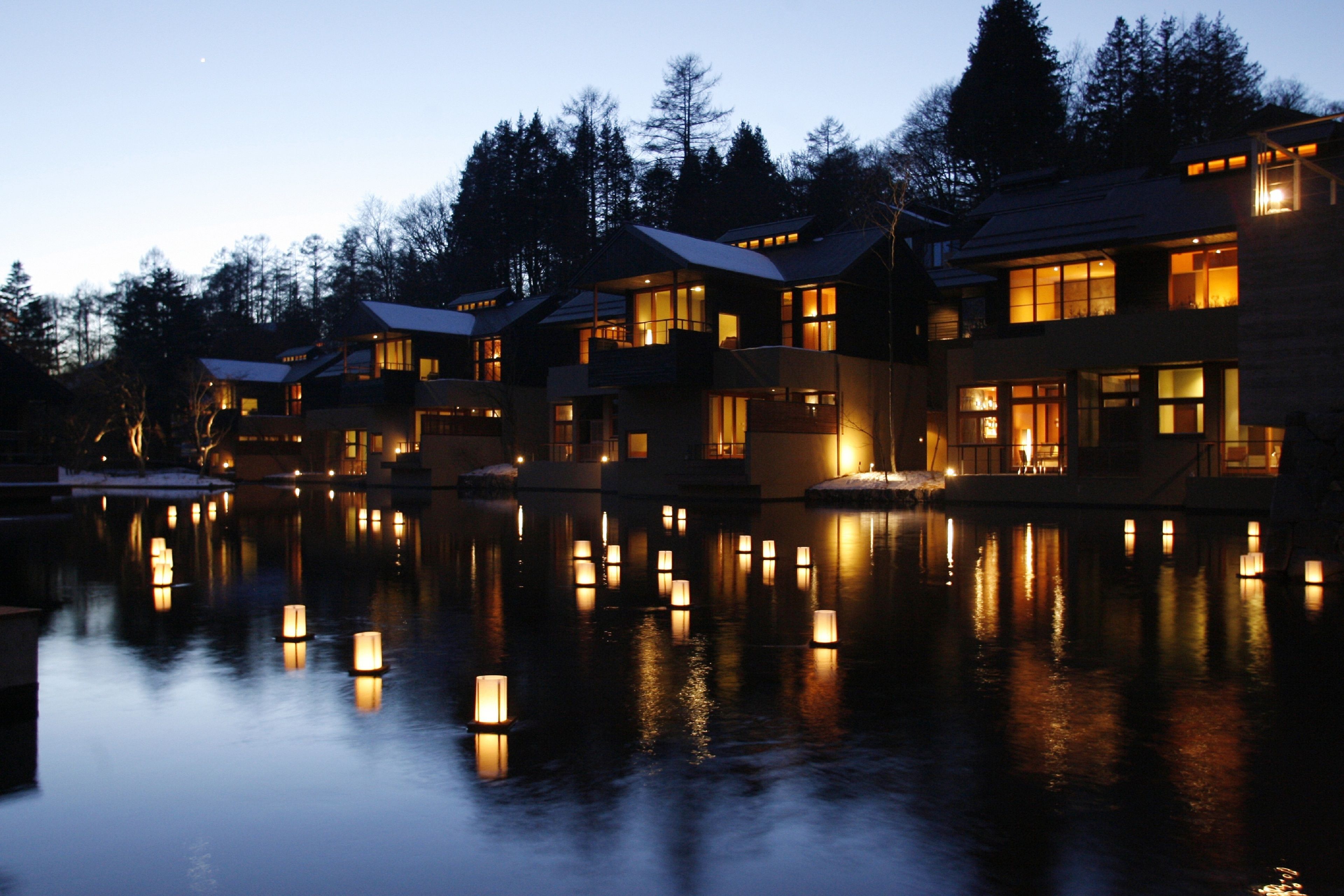A waterfront hotel with multiple buildings, each featuring large windows and a reflection in the water.