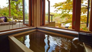 Una piscina interior tranquila con vigas de madera y ventanas amplias que ofrecen vistas del follaje otoñal.