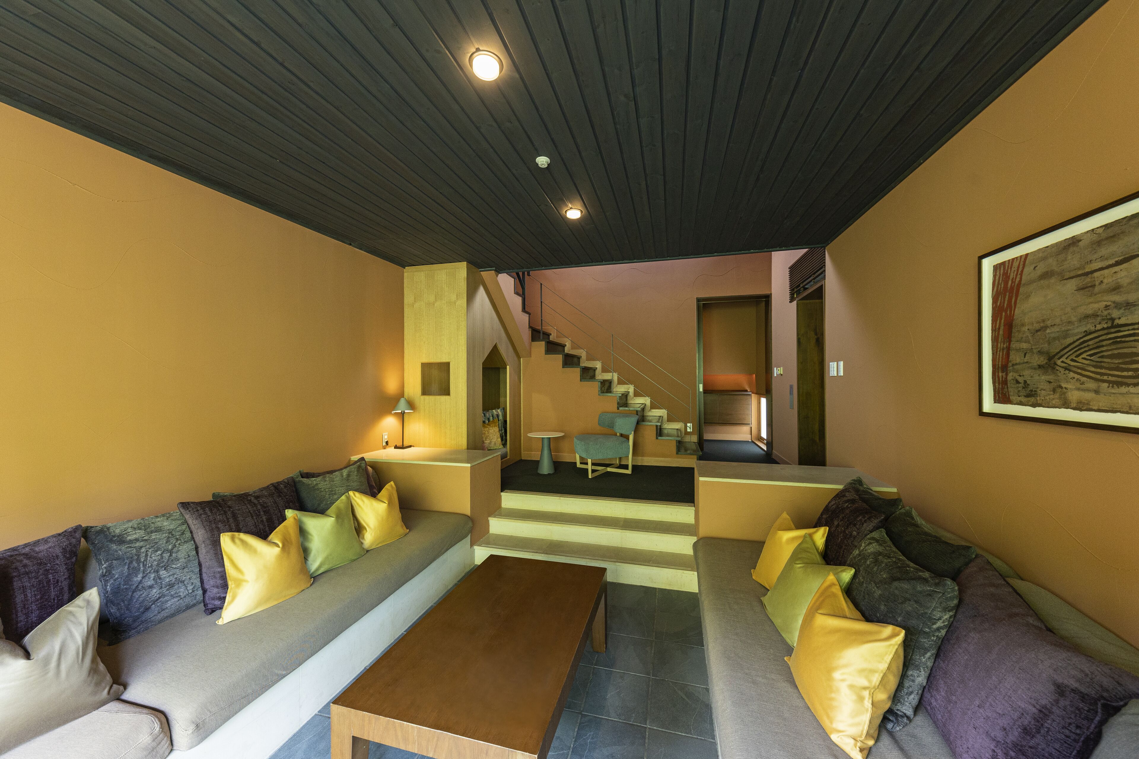 A modern living room with a sofa set, a coffee table, and a staircase leading to another level.