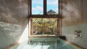 Zona de spa con una bañera de hidromasaje acristalada, paredes de madera y vistas al exterior.