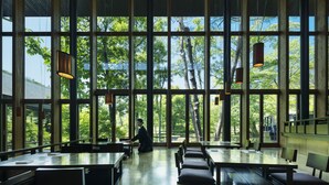 Un comedor amplio con ventanas grandes, mesas de madera y lámparas colgantes.