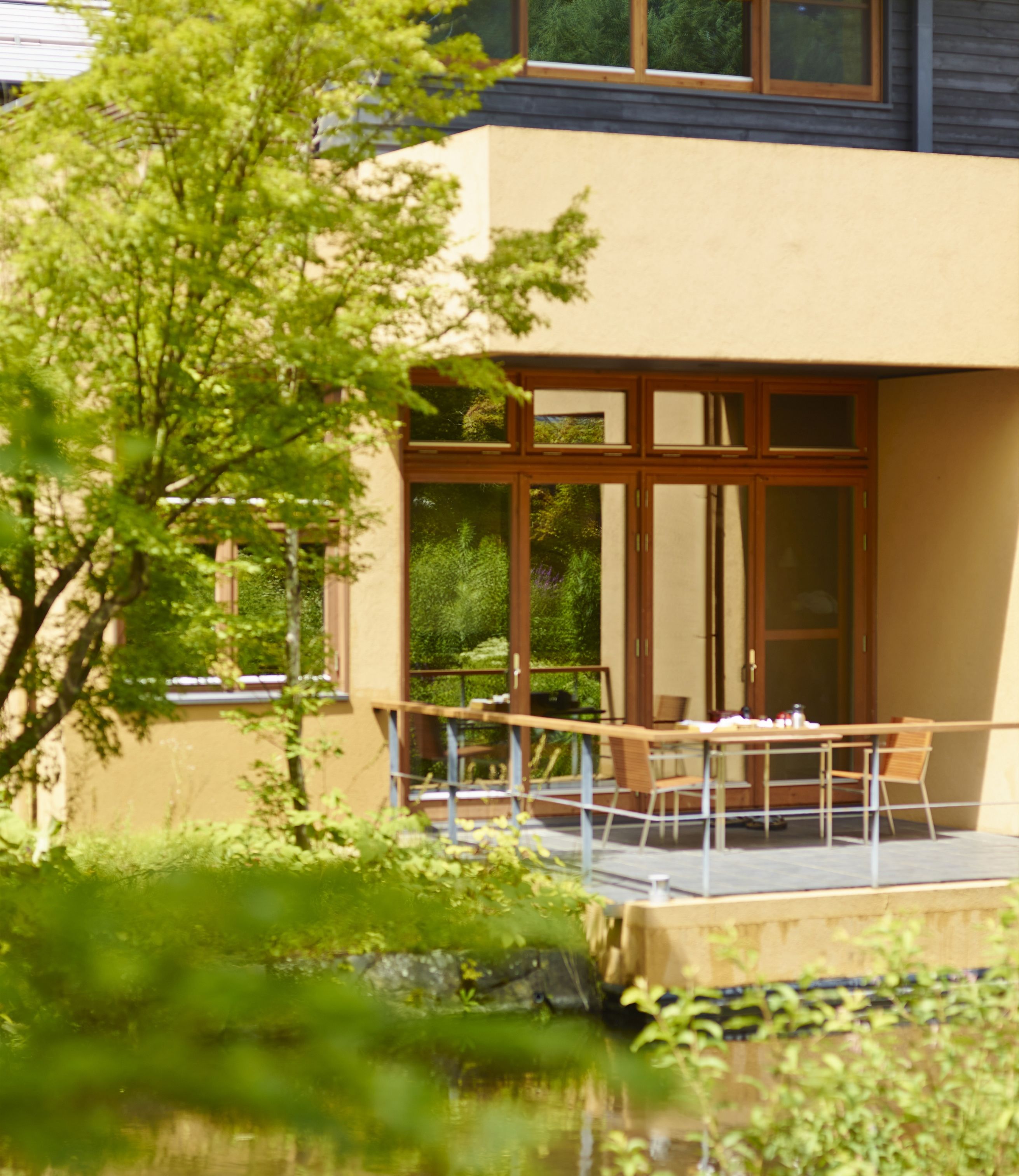 A modern building with large windows and a patio area with outdoor furniture.
