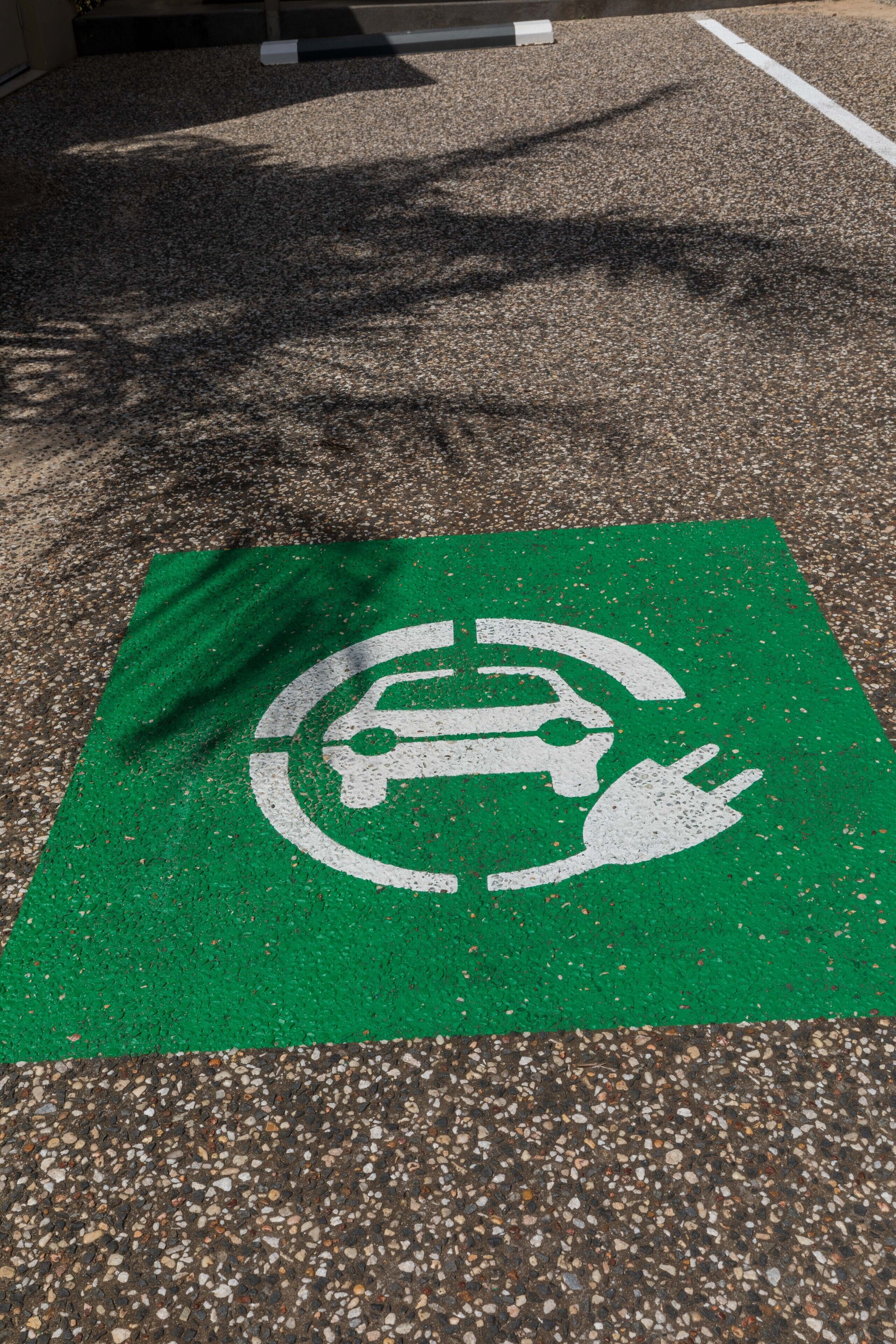 A parking space marked with a green sign indicating electric vehicle charging.