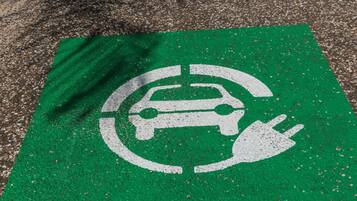 A parking space marked with a green sign indicating electric vehicle charging.