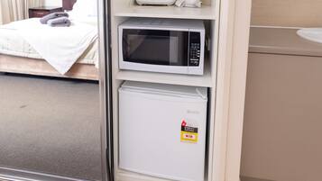 A compact hotel room with a kitchenette including a microwave, toaster, and coffee maker.