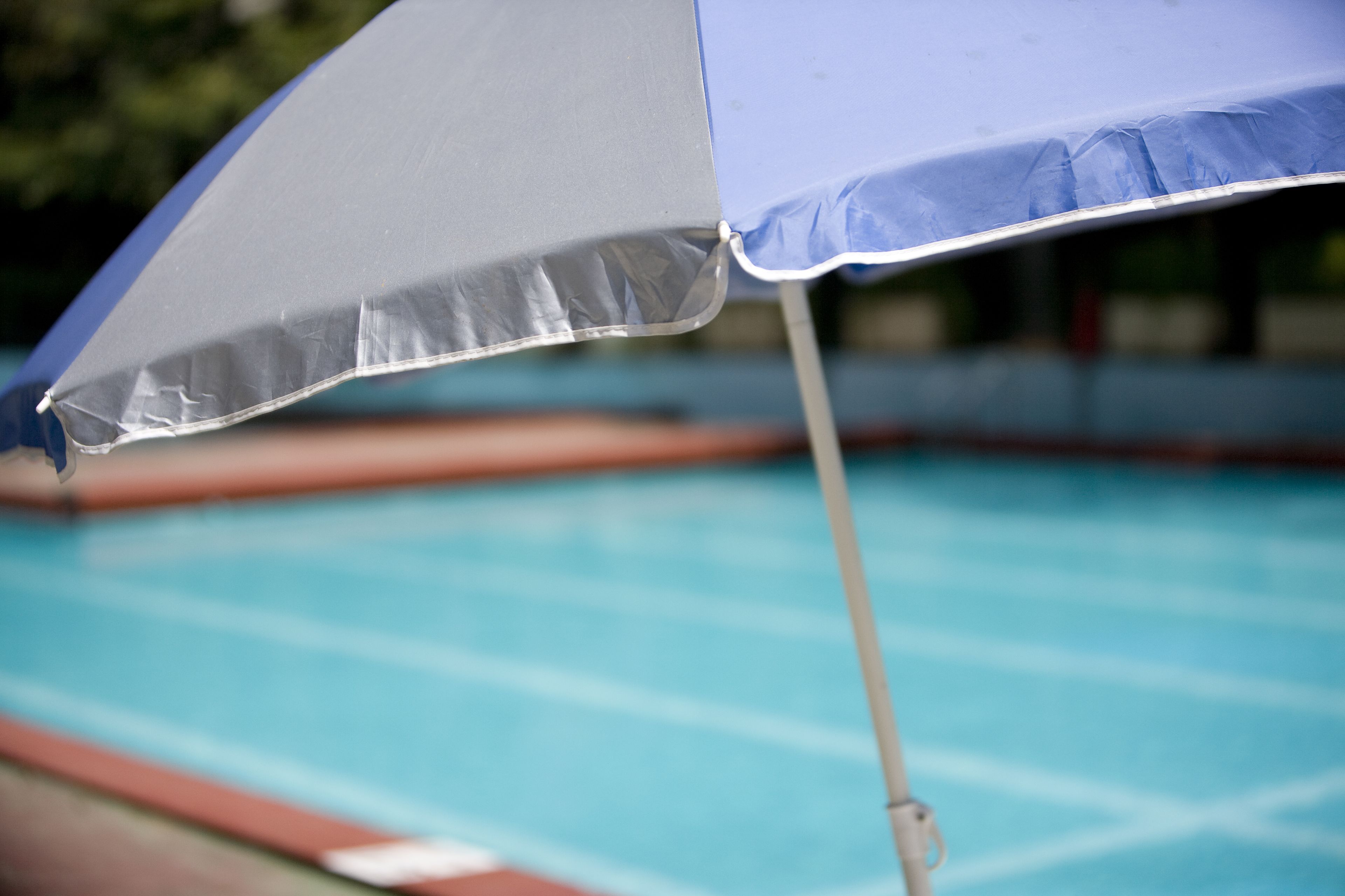 Primer plano de una sombrilla junto a una piscina.