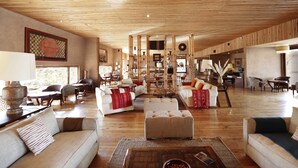 A spacious living area with wooden flooring, white sofas, and a central coffee table.