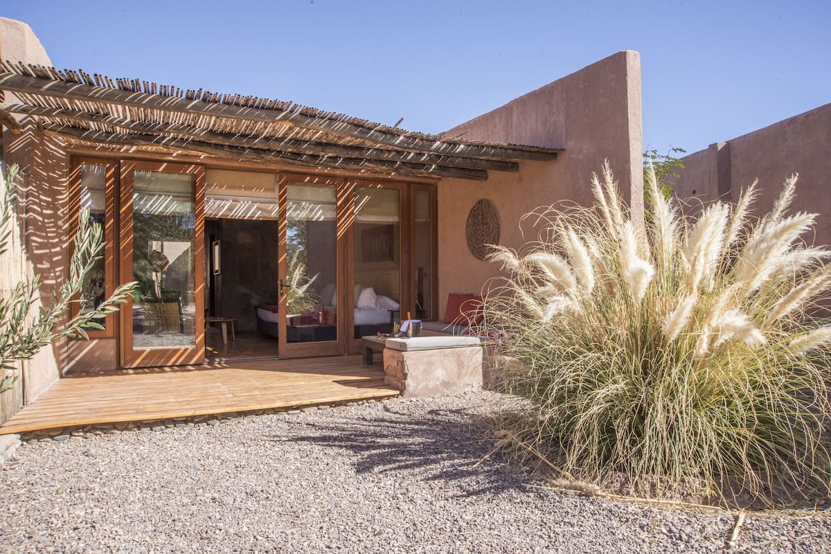 A modern building with a wooden deck, a glass door entrance, and a patio area with a stone table.