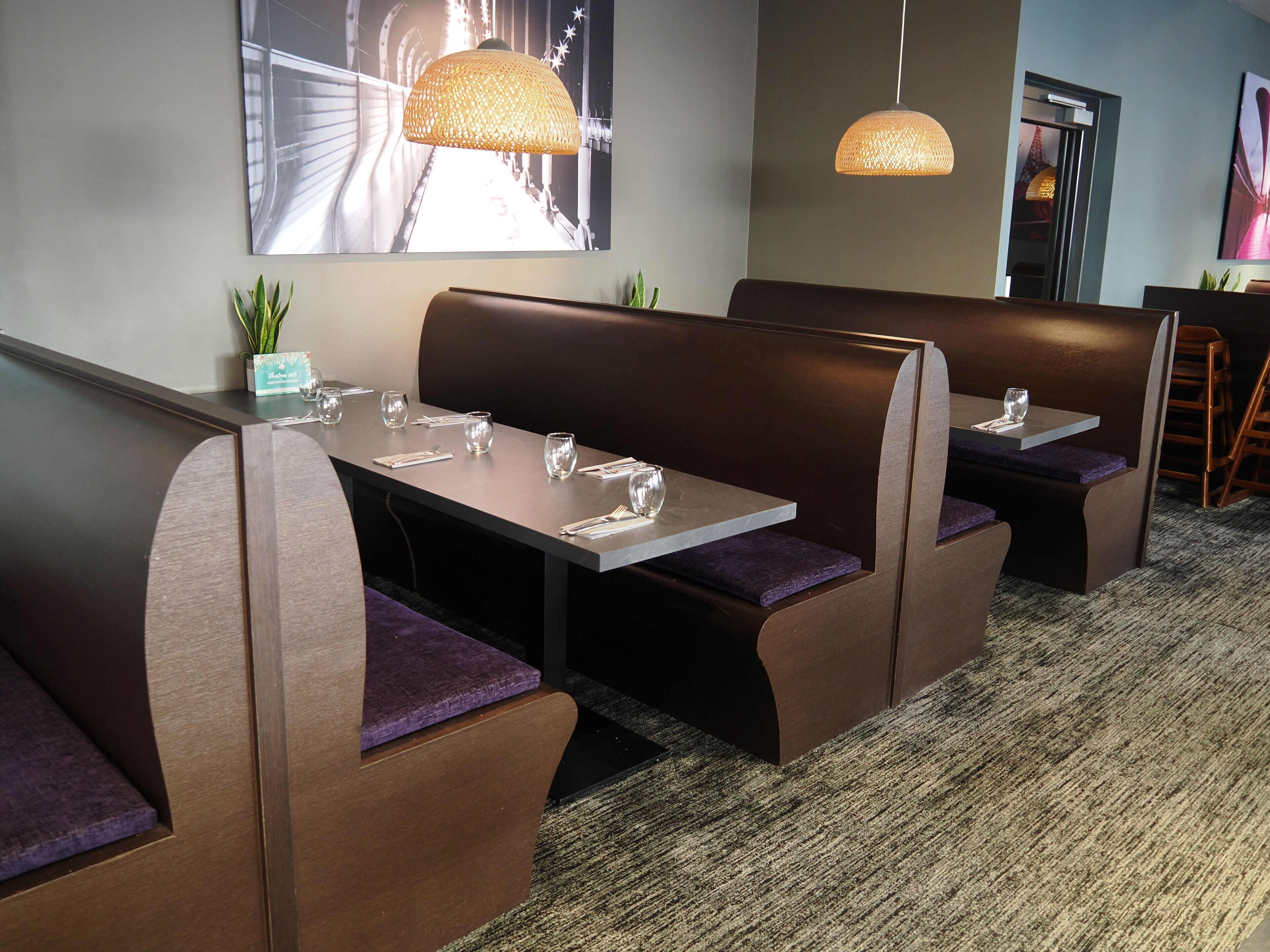 A restaurant with booth seating, a carpeted floor, and a large wall art piece.