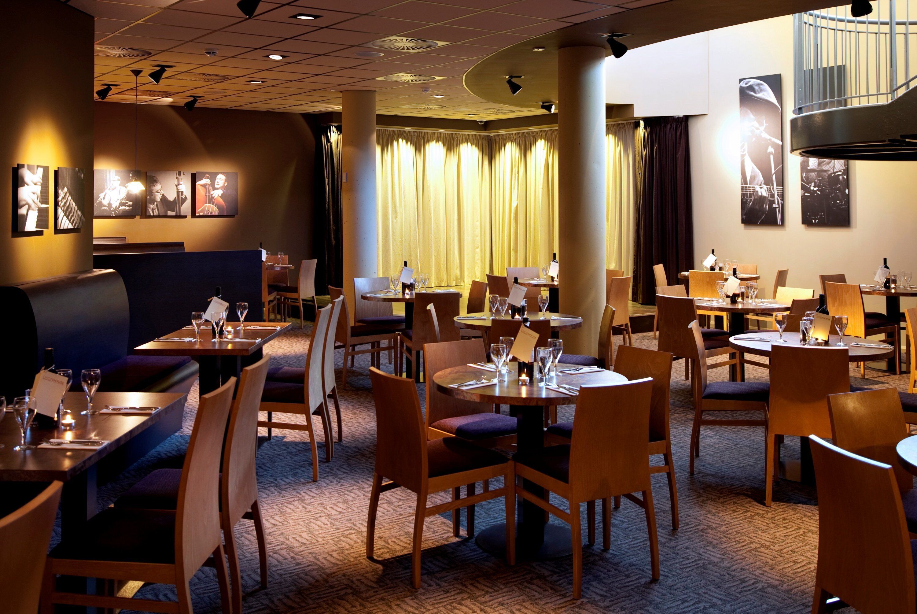 Un restaurant doté de plusieurs tables et chaises, d’un bar et d’un escalier.