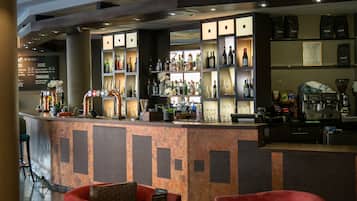 Een bar met een toonbank, flessenrekken en een koffieapparaat.